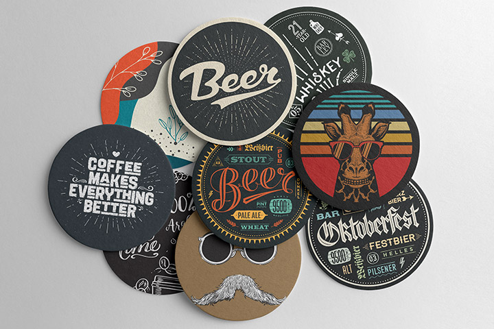 Nahaufnahme von personalisierten Bierdeckeln mit verschiedenen Designs und Logos, die auf einer Theke oder einem Tisch in einer Bar oder Brauerei liegen, um die Markenbekanntheit von Brauereien zu fördern.